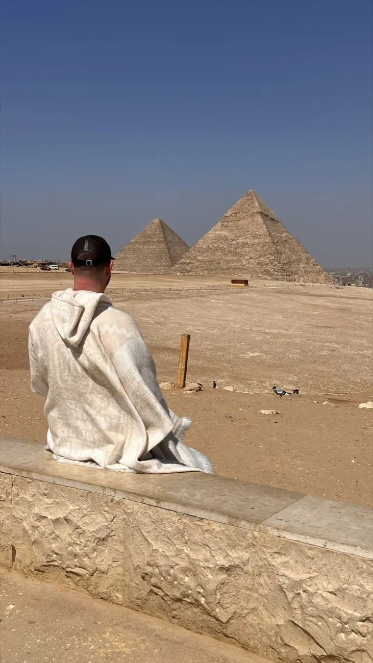Jonas sitting on a stone looking at the Great Pyramid